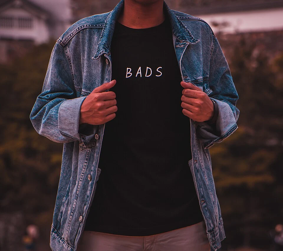 黒いTシャツに青いデニムジャケットを重ねた男性の服装例